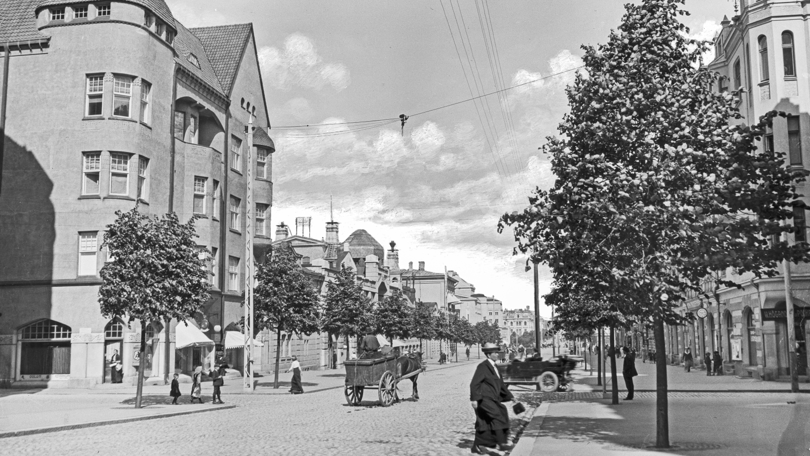 Kuvassa on takana Tampereen tuomiokirkko rakenteilla ja tornissa on rakennustelineitä. Edessä on loivaa kallioita ja edustalla on ihmisiä istumassa ryhmissä ja viettämässä päivää. Kuva on musta-valkoinen.