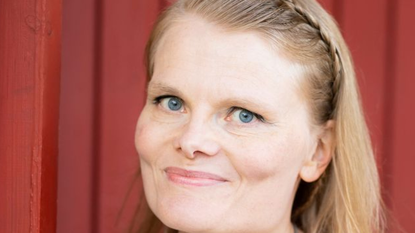 Kuvassa on Annika Aakkulan kasvot ja taustalla on punaista seinää.