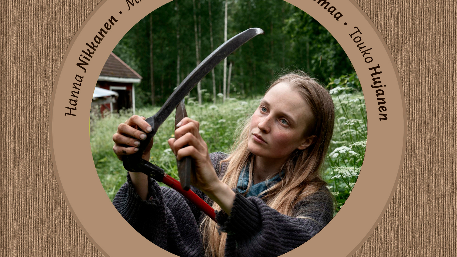 Kuvassa on keskellä ympyrä ja sen sisällä on kuva nuoresta naisesta, joka terottaa viikatetta. Taustalla on vihreää niittyä. Tausta on ruskea ja ympyrän kaarella on tekstiä.