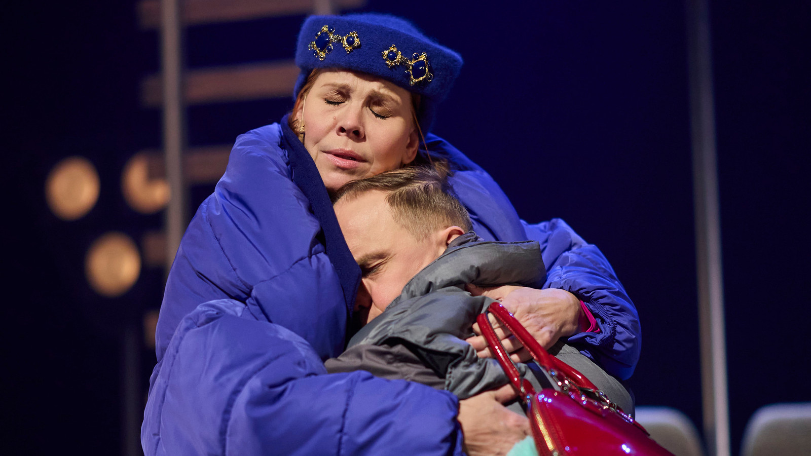 Kuvassa on Eeva Soivio isossa sinisessä toppatakissa ja hän pitää sylissään halauksessa Jarkko Lahtea.