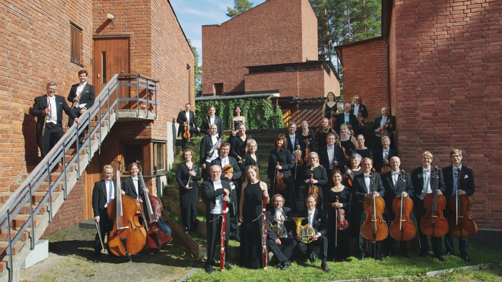 Kuvanssa on Jyväskylän Sinfonian soittajat yhteiskuvassa ulkona punaisten tiilirakenusten edessä riveittäin alhaalta ylöspäin.  Kaksi puhallinsoittajaa on vasemmalla olevilla portailla.    Edessä oikealla ovat sellistit ja vasemmalla basson soittajat.  Taustalta näkyy koivuja ja sinistä taivasta.