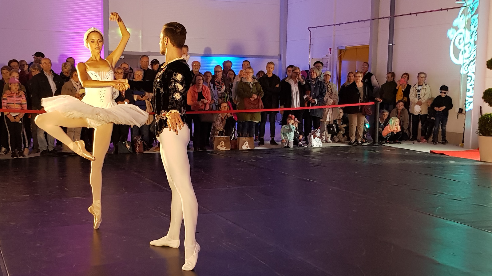 Kuva on Kaakon Kamarimusiikin balettiosuudesta. Kuvassa on Valeria Quintana valkoisessa joutsenpuvussa ja oikea jalka 45 asteen kulmassa.  Hänen vierellään on Alfio Drago mustassa puserossa ja valkoisissa sukkahousuissa.  Taustalla näkyy yleisöä. 