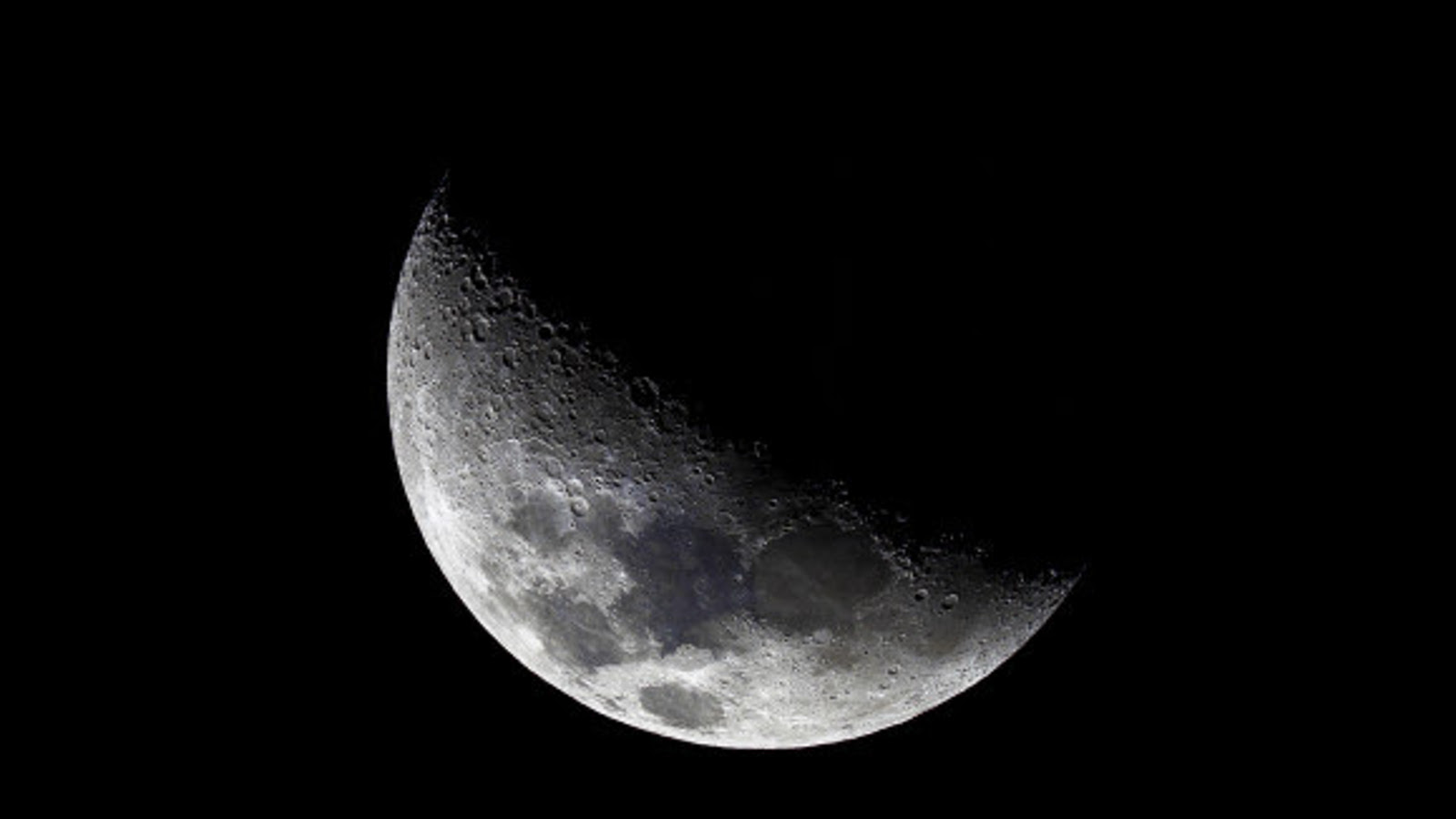 Kuvassa on kuu ja siitä näkyy noin puolet ja osa himmeästi.  Valo näkyy vinosti vasemmalta oikealle.  Muu osa on mustaa musta-valkoisessa kuvassa.