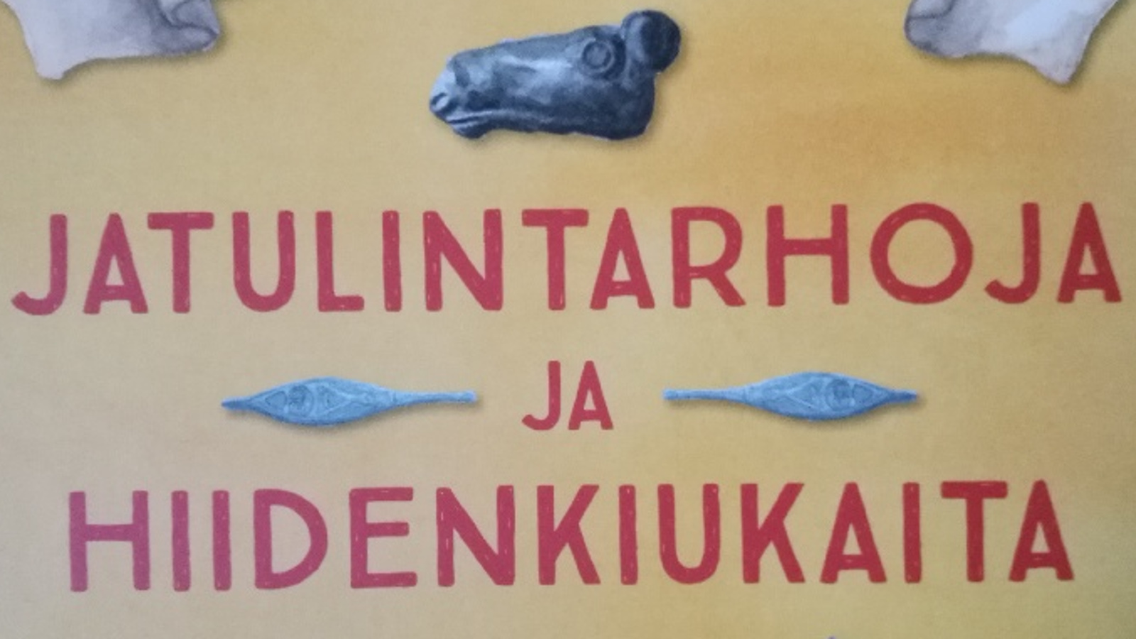 Kuvassa on osa kirjankannesta ja sinä lukee punaisilla isoilla kirjaimilla jatulintarhoja ja hiidenkiukaita.  Tausta on vihertävän keltainen ja tekstien yläpuolella on sininen hirven pään kuva.  Ja -sanan vieressä on molemmin puolin siniset miekan kärjet.