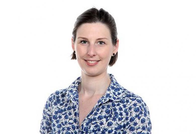 Kuvassa on Elsa Campbell valkopohjaisessa sinikukallisessa, lyhythihaisessa paitapuserossa.  Kuvan tausta on valkoinen.