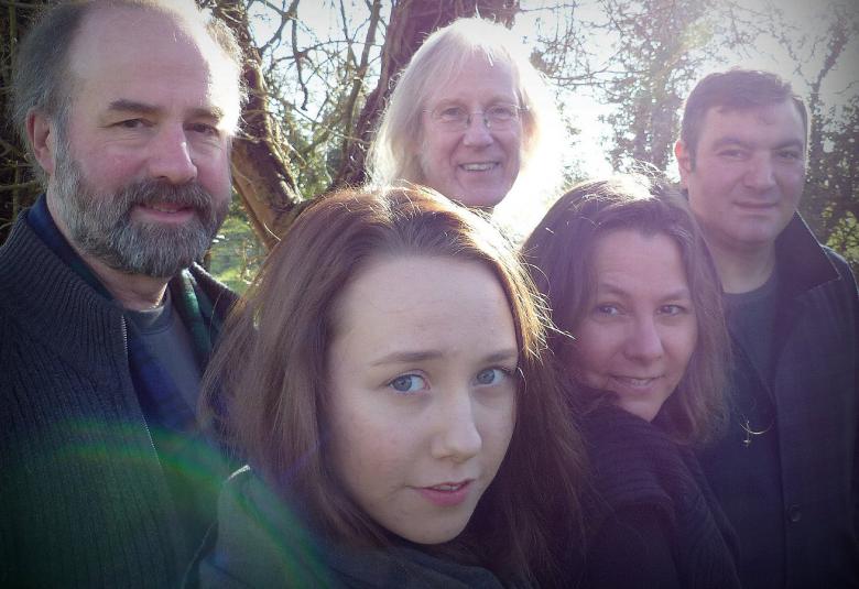 Kuvassa viisi SANS yhtyeen jäsentä, joista kaksi naisia ja kolme miestä. Vasemman puoleisella miehellä on harmaan musta parta. Naiset ovat edessä ja heillä on ruskea tukka.  Kuva  on otettu metsikössä ja henkilöistä näkyy vain kasvot.