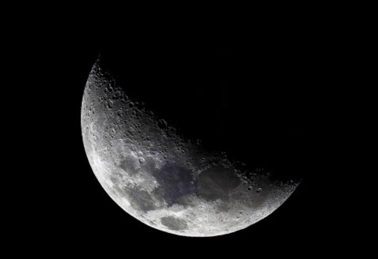 Kuvassa on kuu ja siitä näkyy noin puolet ja osa himmeästi.  Valo näkyy vinosti vasemmalta oikealle.  Muu osa on mustaa musta-valkoisessa kuvassa.