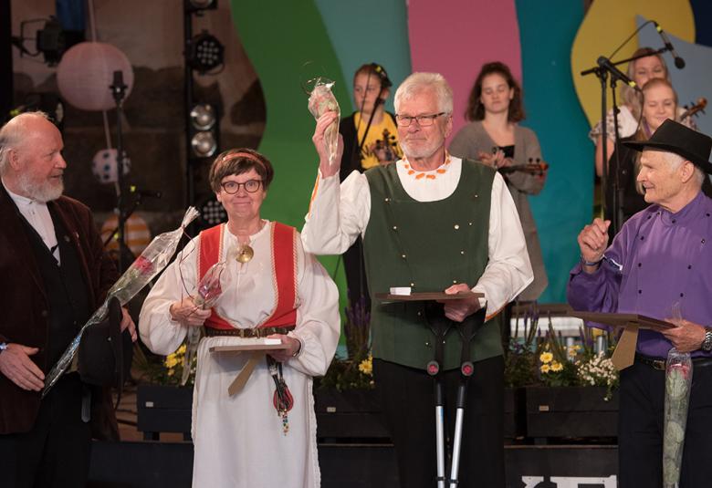 Kuvassa on mestaripelimannit palkintojenjakotilaisuudessa.  Vasemmalla on Toivo Rajala kädessään muovissa oleva ruusu ja päällään tumman ruskW puku ja valkoinen paita.  Hänen vieressään on Ritva Talvitie Pyhäjärven kansallispuvussa, jossa on punaiset olkaimet ja valkoinen paita ja essu.  Vieressä on Aimo Ruisniemi, jolla on musta hattu, violetti paita ja mustat housut.