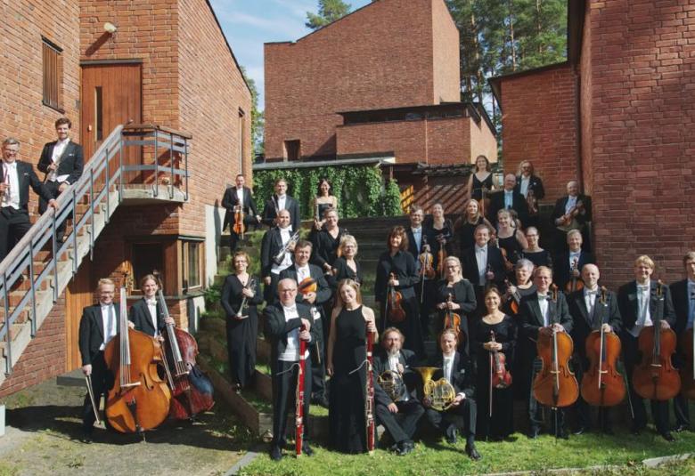 Kuvanssa on Jyväskylän Sinfonian soittajat yhteiskuvassa ulkona punaisten tiilirakenusten edessä riveittäin alhaalta ylöspäin.  Kaksi puhallinsoittajaa on vasemmalla olevilla portailla.    Edessä oikealla ovat sellistit ja vasemmalla basson soittajat.  Taustalta näkyy koivuja ja sinistä taivasta.