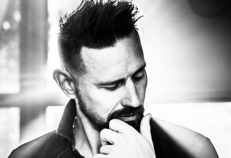 Kuvassa on Lauri Tähkän kasvokuva. Hänellä on pystytukka ja poski- ja leukaparta, jota hän pitelee kädellään.  Tähkän katse on kohti maata.