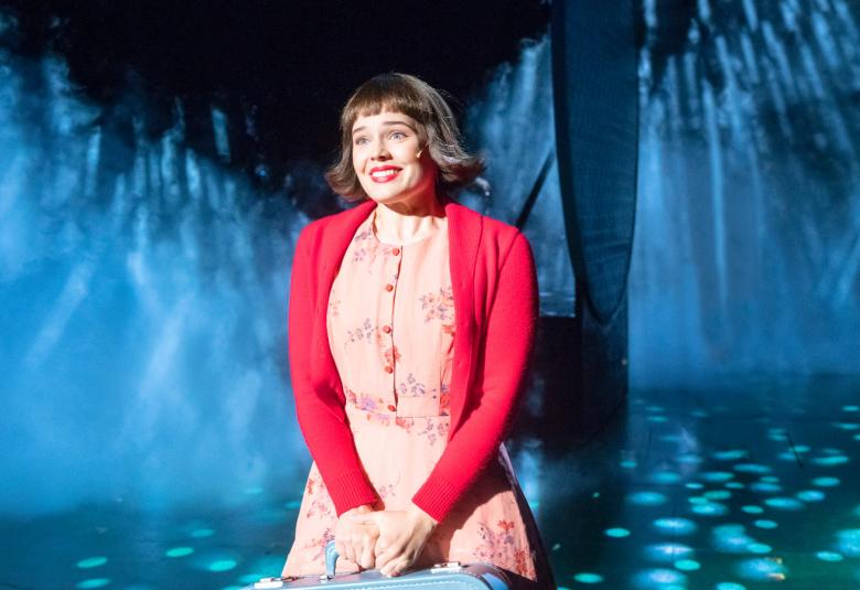 Kuvassa on Marketta Tikkanen, joka on vaaleanpunaisessa kukallisessa mekossa ja punaisessa villatakissa.  Hänellä on tummat puolipitkät hiukset latvasta taivutettuina.  Taustalla on soikeahko pylväs ja osa taustasta on tumma sekä osa sinertävää valaistua.  Lattiassa on valopisteitä tummalla pohjalla.  