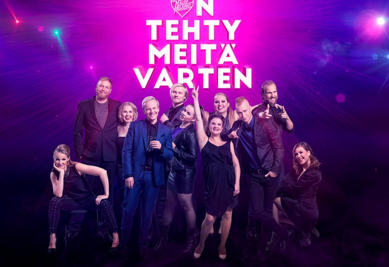 Kuvassa on Maailma on tehty meitä varten -musikaalin näyttelijät ryhmäkuvassa.  Tausta on sininen ja siinä lukee musikaalin nimi on tehty meitä varten.