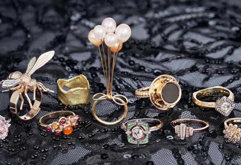 Kuvassa on tumman harmaalla, mustalla korunauhalla päällystetyllä pohjalla kymmenen loppukilpailuun päässyttä sormusta.  Sormukset ovat joko kultaa tai hopeaa ja niitä on koristeltu helmillä tai pienillä kivillä. Yhdessä on päällä sudenkorento. 