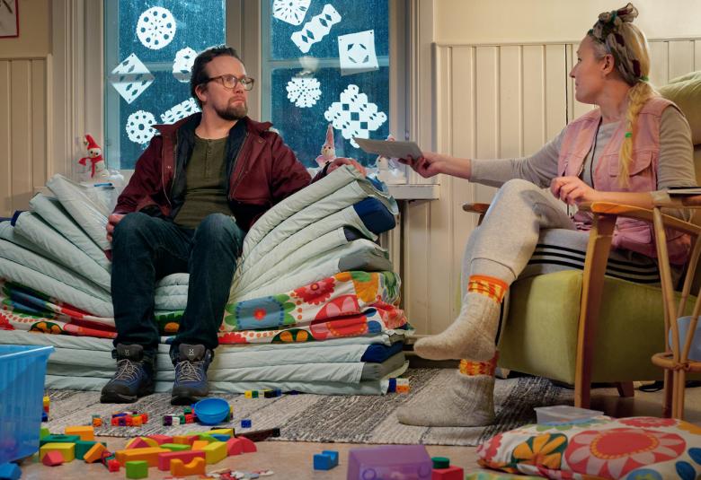 Kuvassa ovat Petteri Summanen ja Mari Hynynen lastentarhan huoneessa, jossa on lattialla leluja.  Summanen istuu patjakasan päällä ja kuuntelee Mari Hynystä.