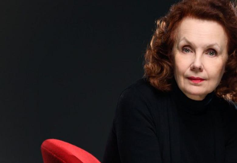 Kuvassa on Kaija Saariaho ja kuvan tausta on tumma. Saariaho on kuvan oikeassa laidassa.