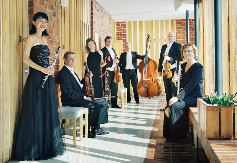 Kuvassa on Jyväskylä Sinfonia käytävässä ja orkesterin jäsenet seisovat.  Kaikilla on esiintymisasut päällä.  