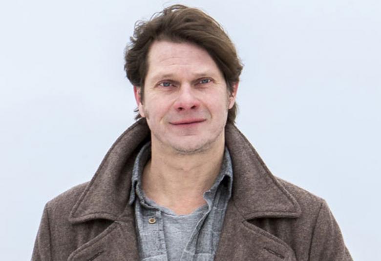 Kuvassa on Kari-Pekka Toivonen puolivartalokuvassa.  Kuva on otettu ulkona ja Toivosella on ulkotakki ja napit auki.  Tausta on vaalea.