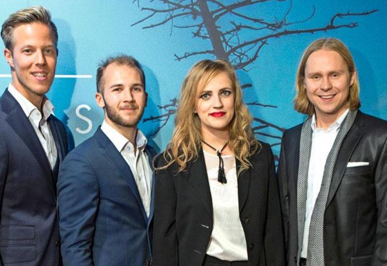 Kuvassa on Haloo Helsingin esiintyjät yhteiskuvassa.  Kuvan tausta on sininen ja siinä on puiden  paljaita oksia.