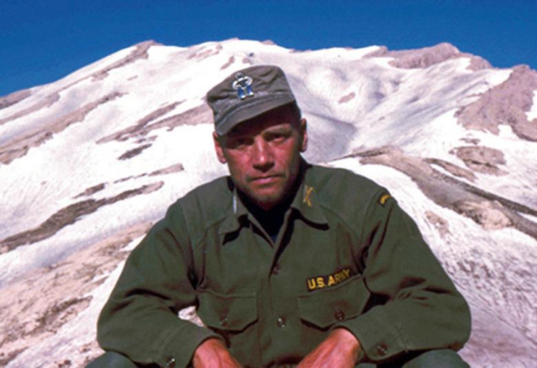 Kuvassa on noin 40-vuotias Lauri Törni eli Larry Thorne USA:n sotilaspuvussa. Kuva on otettu vuoristossa ja Törnistä on puolivartalokuva aurinkoisella ilmalla.