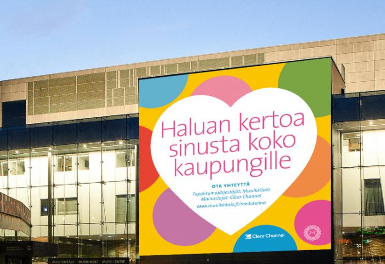 Kuvassa on Musiikitalon seinä, jossa on mediaseinässä väripallojen päällä valkoisessa sydämessä on teksti: Voisin kertoa sinusta koko kaupungille.