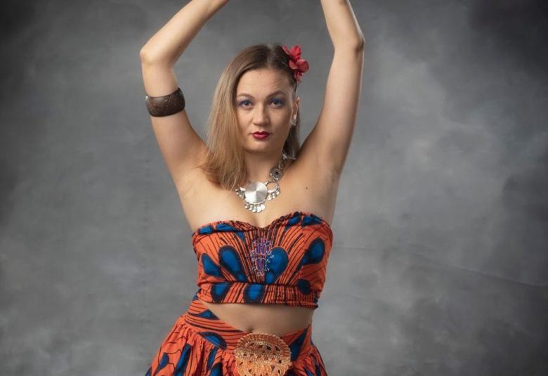 Kuvassa on nainen kädet ylhäällä ja vartalon myötäisessä mekossa.   