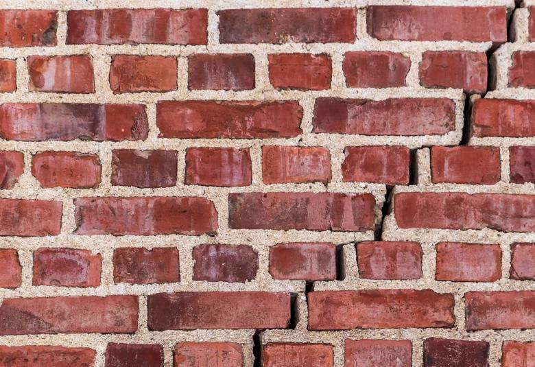 Kuvassa on tiiliseinää, jossa on vinosti keskellä menevä repeämä.