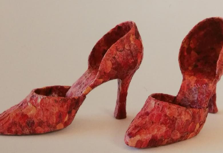 Kuvassa on punaiset kengät, jotka on tehty puolukanlehdistä. Kengissä on korot ja kapeat kärjet.
