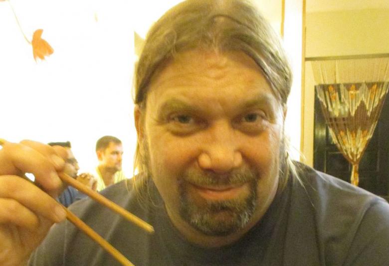 Kuvassa on Ralf Andtbacka ja hänellä on syömäpuikot kädessään.  Hänestä on kasvokuva. 