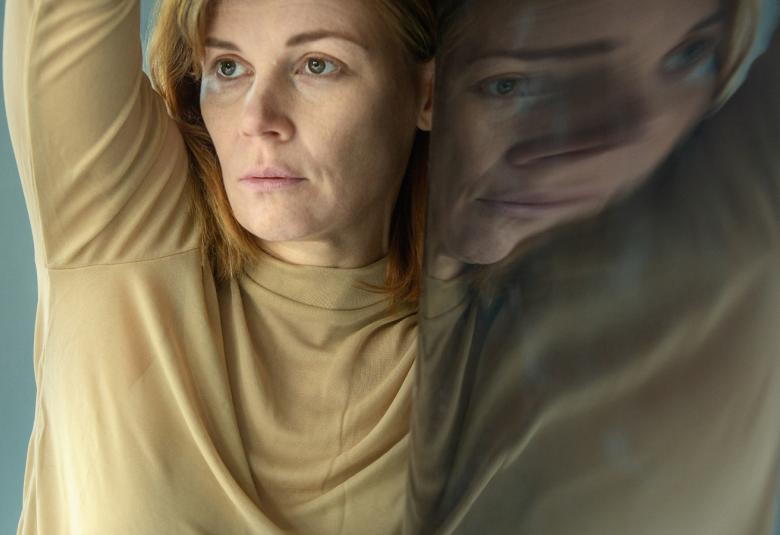 Kuvassa on Jenni-Elina von Bagh tanssiasennossa kädet ylhäällä.  Päällään hänellä on vaalean ja harmaan vihertävä viittamainen pusero.