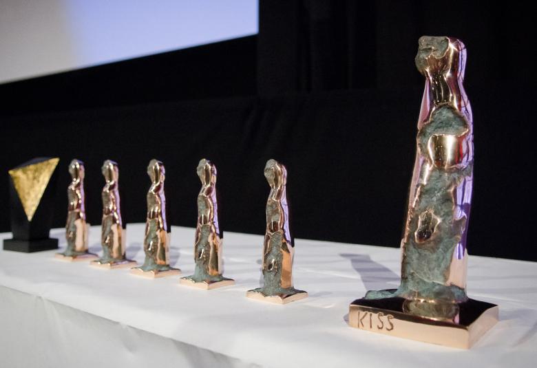 Kuvassa on Tampereen elovajuhlien palkintoja vuodelta 2019 ja ne ovat pöydällä valkoisella liinalla. Patsaat ovat pronssisia ja suurimmaksi osaksi kullattuja.