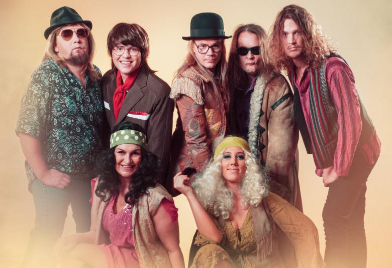 Kuvassa ovat musikaalin esiintyjät 1970-luvun vaatteissa iloisella ilmeellä.  