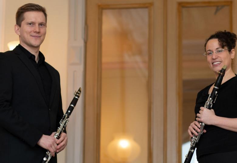 Kuvassa on kaksi klarinetistia, joista vasemmalla on mies klarinetti kädessään ja oikealla nainen myös klarinetti kädessään. 