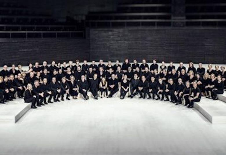 Kuvassa on Radion sinfoniaorkesteri yhteiskuvassa levittäytyneenä istumaan orkesterikorokkeelle. 