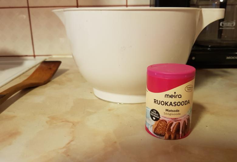 Kuvassa on soodapurkki ja takana vatkauskulho.  Taaempana on kahvinkeitin ja sivulla puulasta.