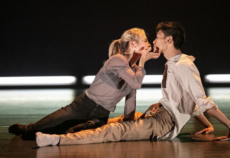 Kuvassa on nais- ja miestanssijat lattialla istumassa vastakkain ja kasvot intiimisti vastakkain.  