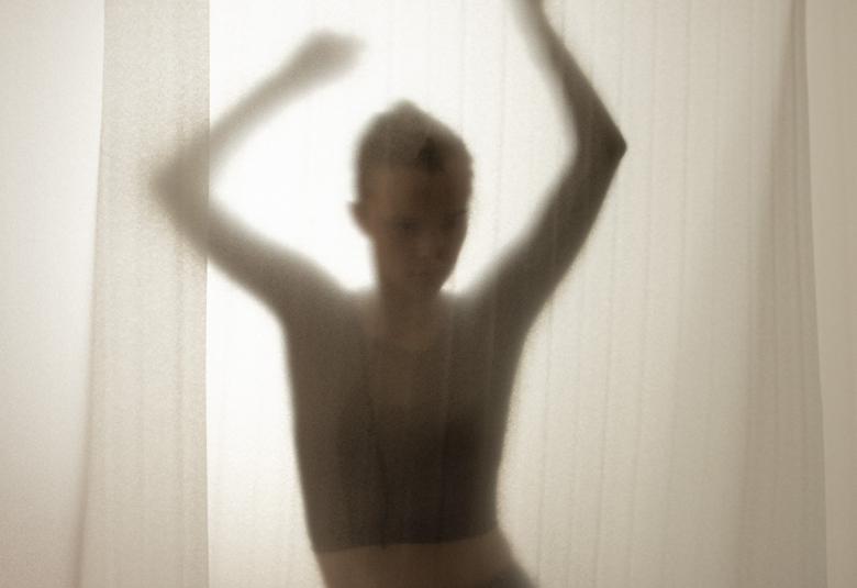 uvassa on tanssijan hahmo, joka näkyy vaalean läpinäkyvän verhon takaa.