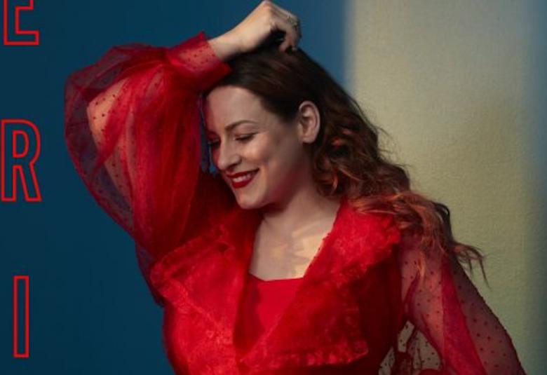 Kuvassa on Erin ja hän katsoo alaspäin. Hänellä on päällään punainen mekko.