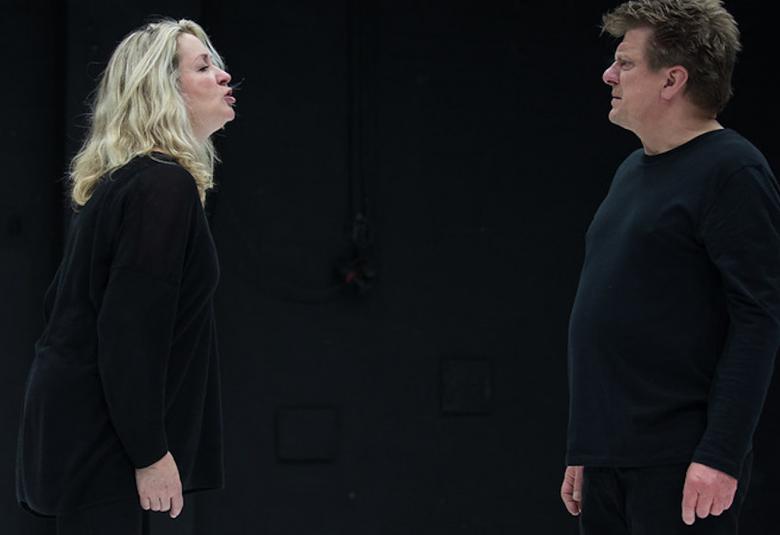 Kuvassa Katariina Kaitue ja Timo Torikka seisomassa vastakkain ja keskustelemassa vakavan näköisinä. Tausta on musta.