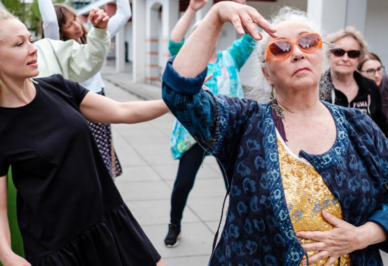 Kuvassa on kaksi naista tanssimassa kadulla ja taustalla näkyy kasi tanssijaa lisää.