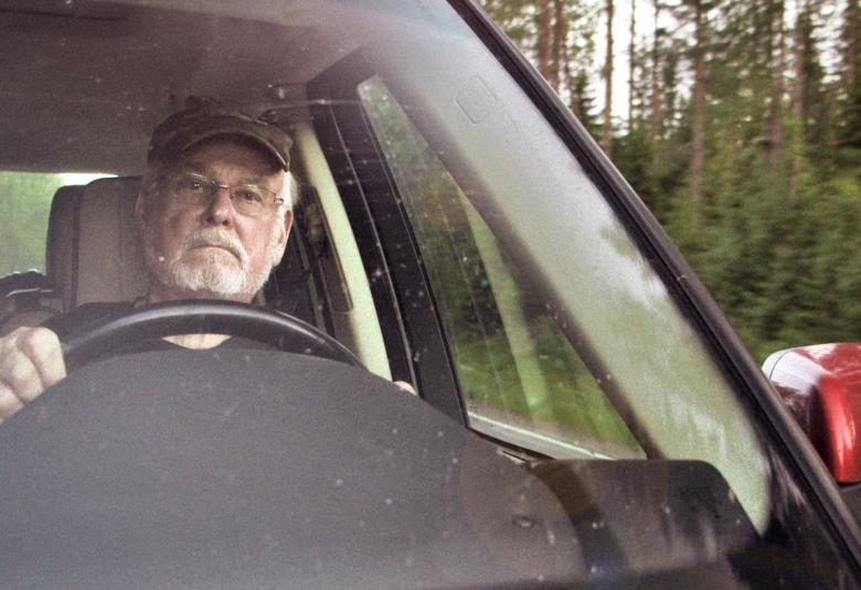 Kuvassa on elokuvasta otettu kuva Hannu Karposta ajamassa autoa.  Kuva on edestä ja tuulilasin takaa näkyy Karpo.
