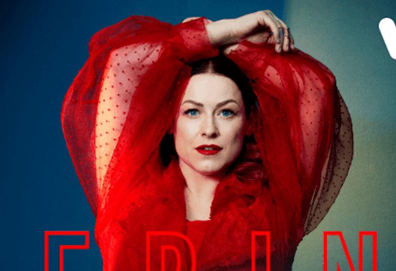 Kuvassa on Erin punaisessa puserossa kädet ylhäällä.