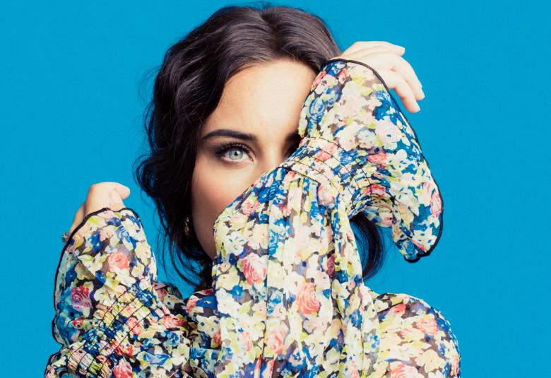 Kuvassa on Abreu ja hän katsoo kätensä takaa kukallisessa puserossa.  