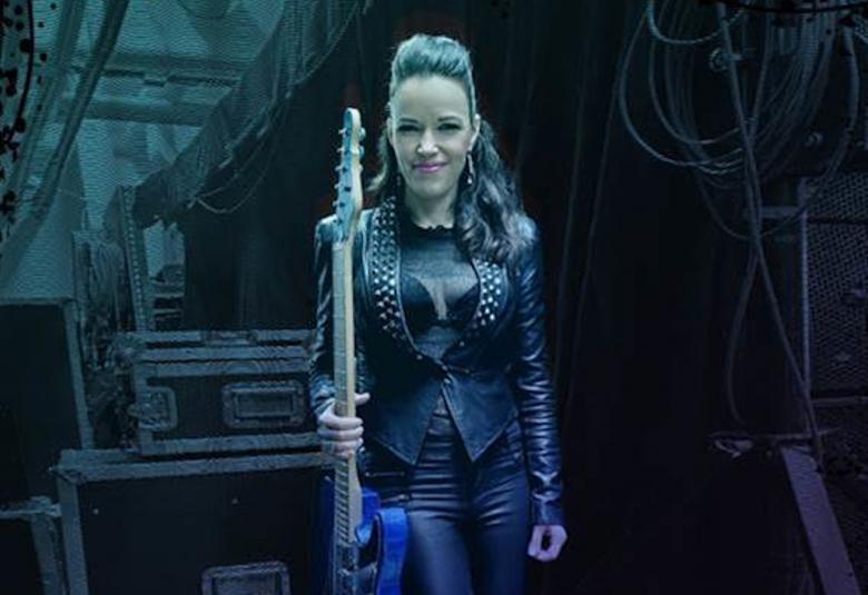 Kuvassa on Erja Lyytinen seisomassa kitara kädessään pystysuorasti.