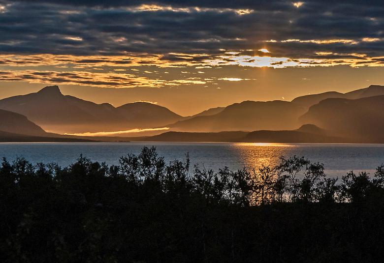 Kuvassa on iltaaurinko Kilpisjärvellä. Yllä on siniharmaata taivasta.