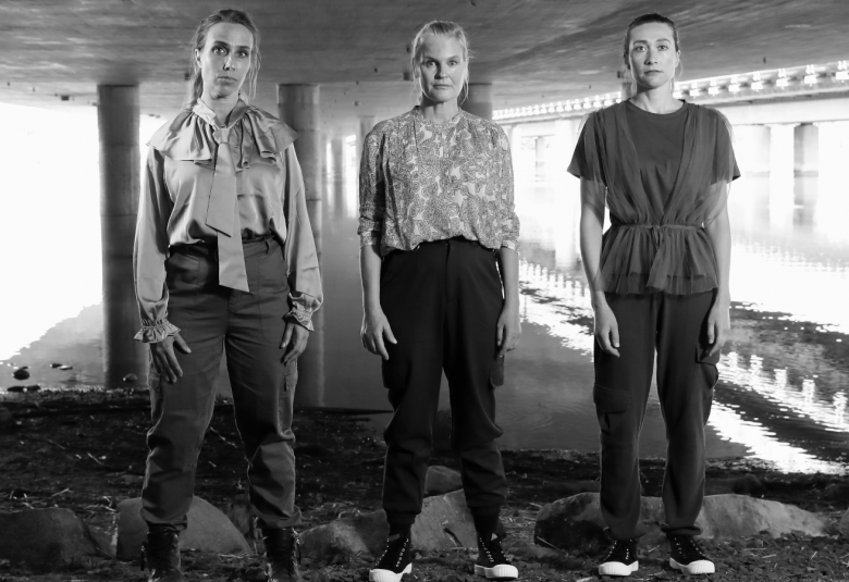 Kuvassa ovat näyttelijät Anna Ranta, Mona Kortelampi ja Asta Rentola seisomassa kivellä matalan betonisillan alla.  Takana näkyy vettä.