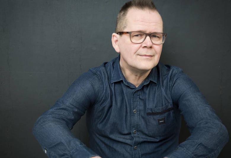 Kuvassa on Kari Hotakainen istumassa ja kuva on puolivartalokuva.
