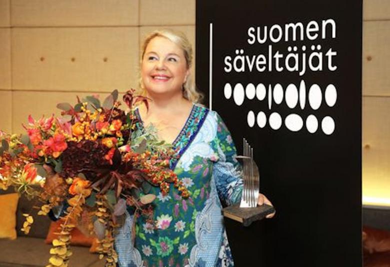 Kuvassa on Anu Komsi runsaiden palkintokukkien kanssa.