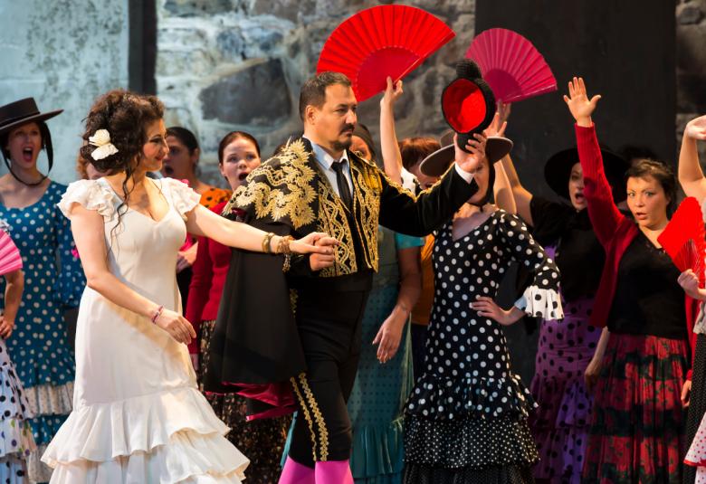 Kuvassa on kohtaus Carmenista ja keskellä Nadia Krasteva ja Randall Jakobsh muun laulajajoukon keskellä.