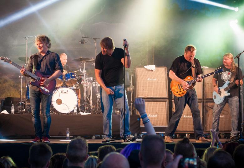 Kuvassa on Eppu Normaali esiintymässä lavalla, jossa on savua ja punavaloa.