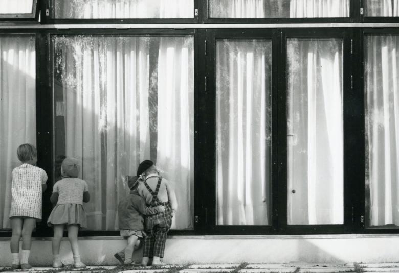 Kuvassa on Otonpesä Tapiolassa ja rakennuksessa on suuret ikkunat.  Lapset kurkkivat ikkunasta.